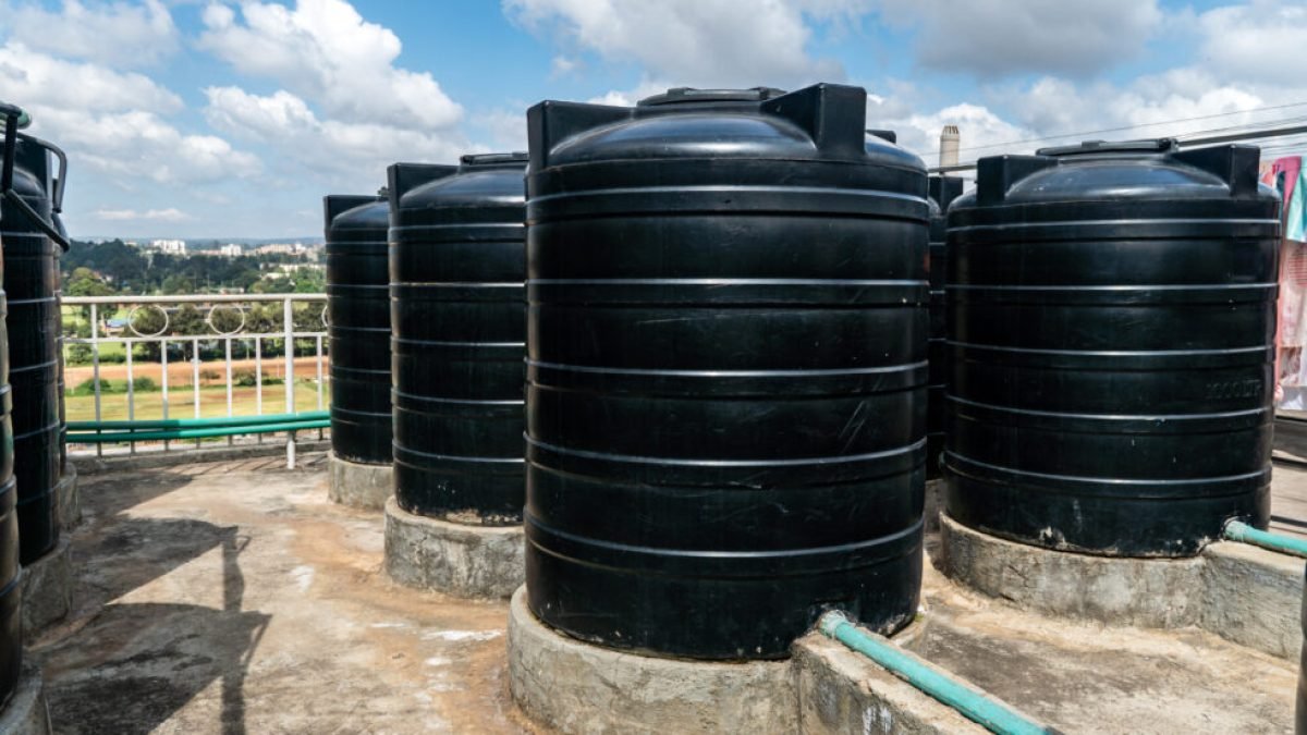 city roofs are occupied by black water storage tanks. Water tank on roof in Africa. Water heating tank against sea and the city. Asian water supply and heating system